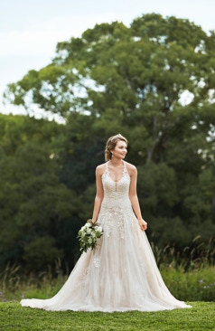 Ein romantisches A- Linien Brautkleid. Das Kleid hat einen tiefen V- Ausschnitt sowie transparente Spitzenträger, die einen quadratischen Schlüsselloch Effekt im Rückenbereich erzeugen. Das Tüll- Brautkleid ist mit Perlen- Spitzenapplikationen verziert, die im Rock sanft hinunter laufen. Zu schließen ist das Kleid mit einer Schnürung im Rückenbereich. 