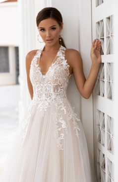 Ein modernes und romantischen Brautkleid aus weich fallenden Tüll, kombiniert mit einem V-Ausschnitt und transparenten Trägern auf dem Rücken. 