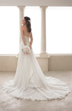 Ein zartes aber dennoch verführerisches A- Linien Hochzeitskleid aus Chiffon. Das Kleid hat einen trägerlosen herzförmigen Ausschnitt. Das gesamte Oberteil des Brautkleides ist mit Spitzenapplikationen verziert. Ein Hingucker des Kleides ist der geraffte Rock mit den fließenden unterschiedlichen wellenartigen Chiffonlagen, die sich auch in der Schleppe wiederfinden. Das Brautkleid lässt sich durch eine Schnürung im Rückenbereich schließen. Optional ist das Kleid auch mit einem Reißverschluss und Kristallknöpfen erhältlich. 