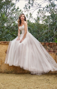 Ein wunderschönes Hochzeitskleid im Prinzessin Stil. Das hier zusehende Brautkleid verfügt über einen trägerlosen herzförmiges Ausschnitt und einem halbtransparentem Oberteil. Das Oberteil ist reichlich mit modernen perlenbestickten Spitzenapplikationen verziert. Auch hat das Prinzessinnen-Kleid einen voluminös gerafften Rock aus weichem Tüll sowie Paillettentüll und einer schönen Schleppe. Abnehmbare Träger sind bei dem Kleid enthalten. 