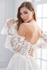 Frau in einem weißen, schulterfreien Hochzeitskleid mit Spitzenärmeln, erhältlich bei FM Braut- und Abendmode in Sandkrug bei Oldenburg. 