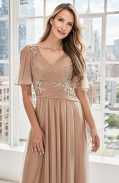 Elegantes Abendkleid FM52283 in zartem Salbeigrün aus fließendem Chiffon mit V-Ausschnitt, zarten Flügelärmeln und floralen Stickereien – erhältlich bei FM Braut- und Abendmode in Sandkrug bei Oldenburg.