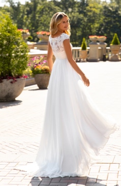 Boho-Brautkleid mit einem modernen Touch. Das Oberteil ist mit Pailletten besetzter Spitze verziert und mit einem leichten Chiffonrock kombiniert.